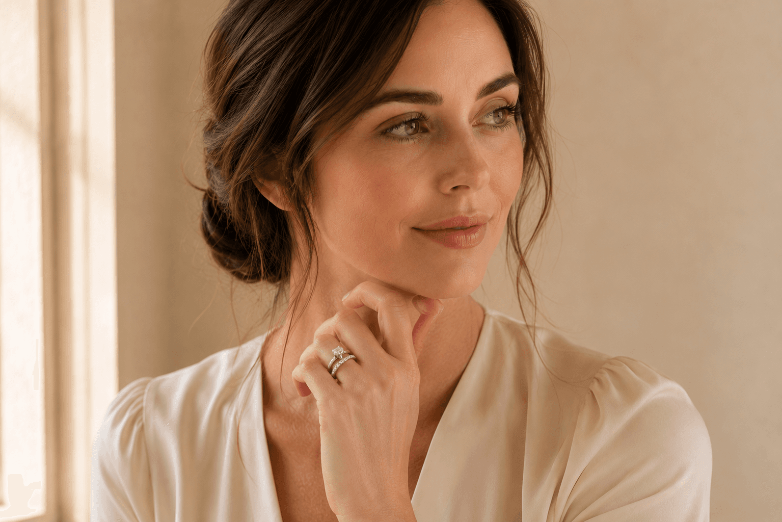 Woman wearing a diamond eternity anniversary band stacked with her engagement ring, hand resting on cream silk