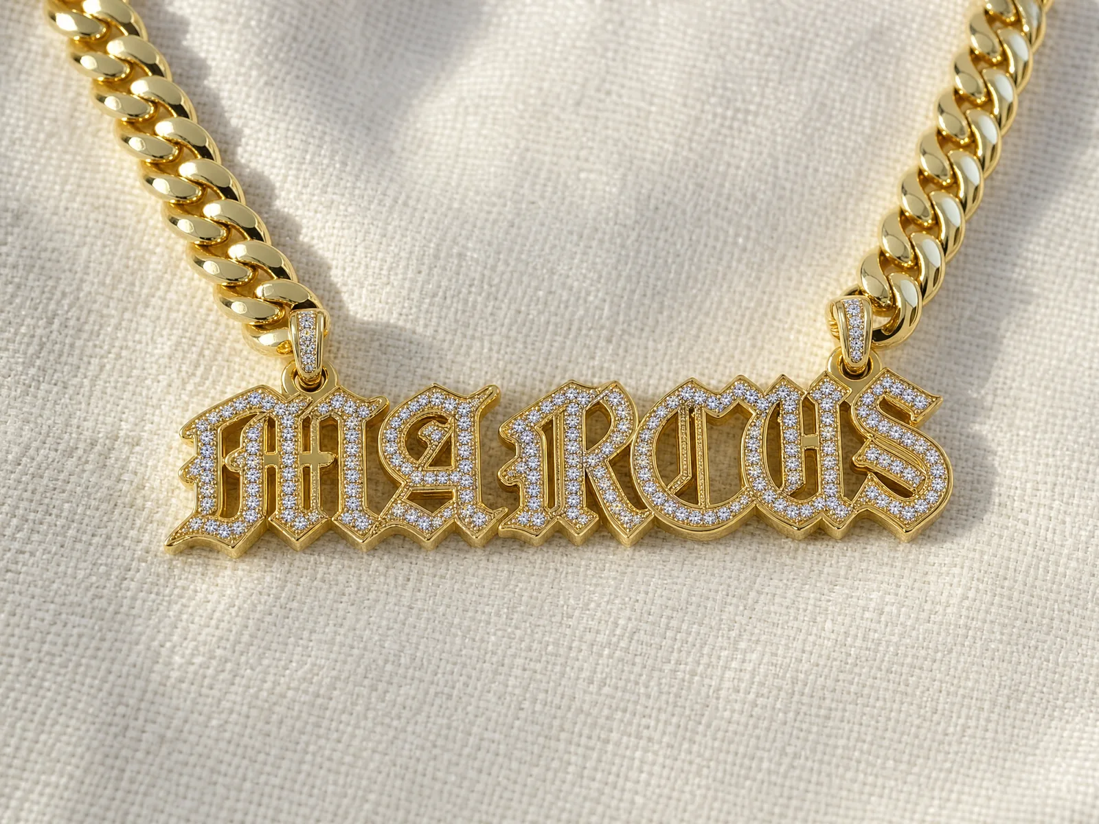 A gold nameplate necklace on a heavy Cuban link chain, the name cut in gothic capitals with each letter outlined in pave-set diamonds