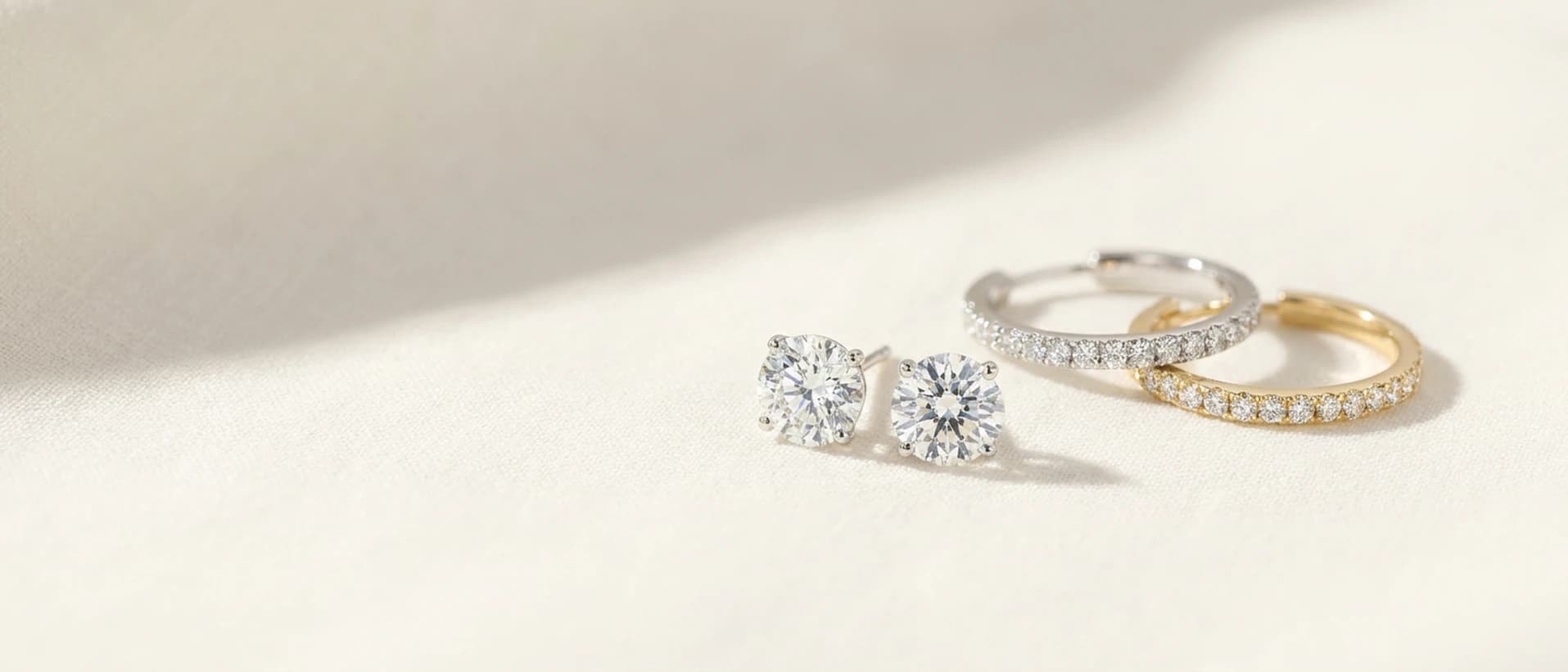 Diamond stud and hoop earrings on cream linen at ATL Luxury Jewelry Atlanta