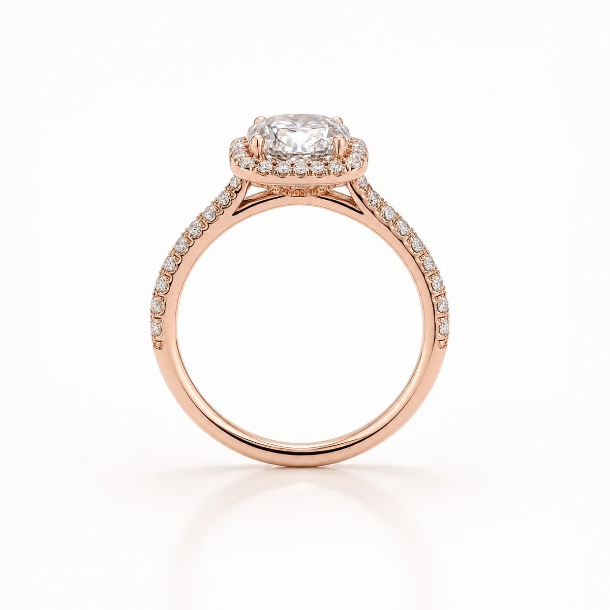 A rose gold ring standing upright on a pale background, a cushion-cut centre diamond framed by a pave halo with pave continuing along the shoulders