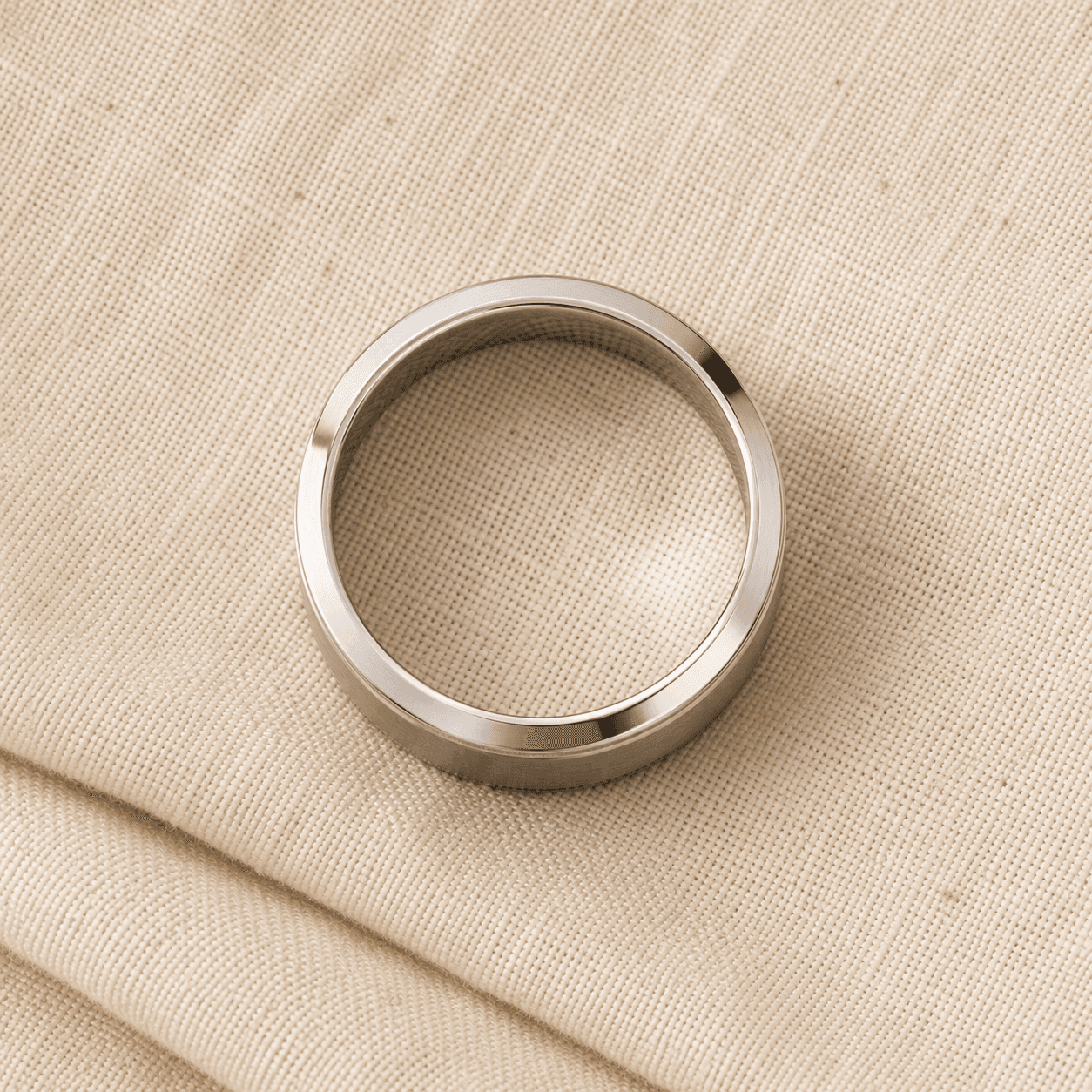 Men's brushed platinum wedding band on cream linen at ATL Luxury Jewelers Atlanta