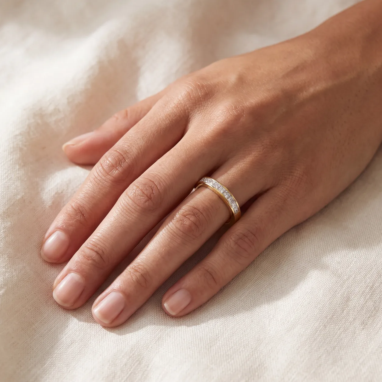 A hand wearing a ring set with a colored gemstone, a traditional anniversary stone.