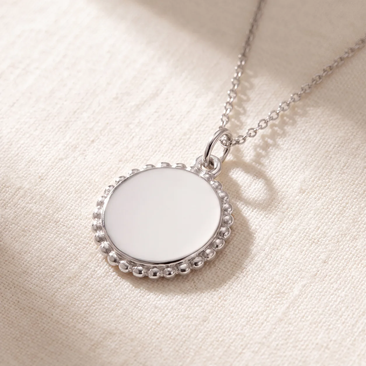 A gold pendant necklace with an engraved disc