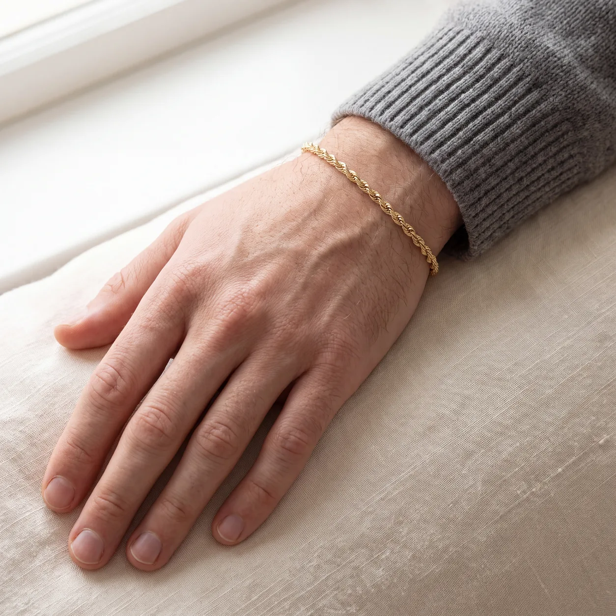 A men's silver chain and a thin gold bracelet on slate, styled as an easy first jewelry gift