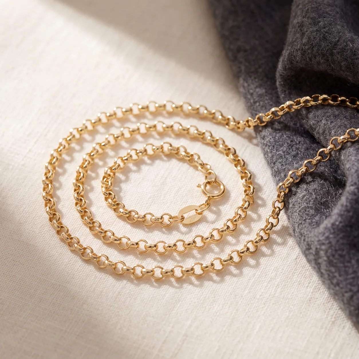 A coiled gold rolo chain necklace on cream linen
