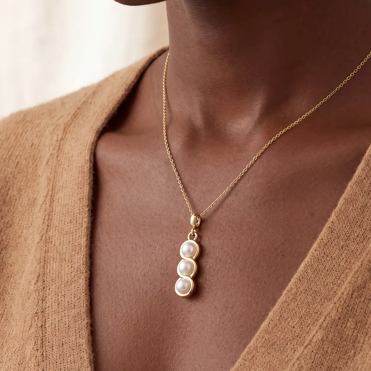 A gold necklace with three graduated pearls worn at the neckline