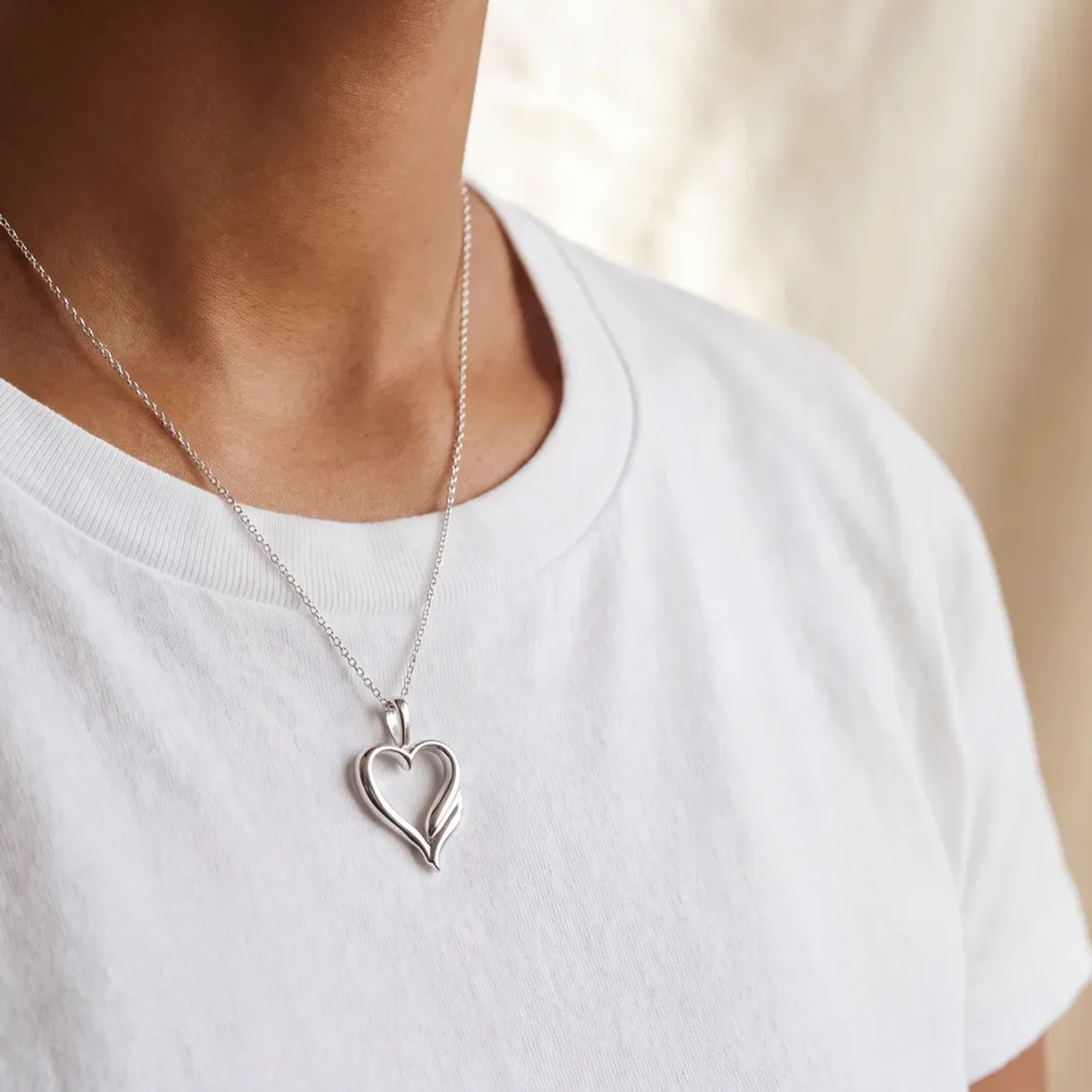 A silver heart pendant necklace worn at the collarbone