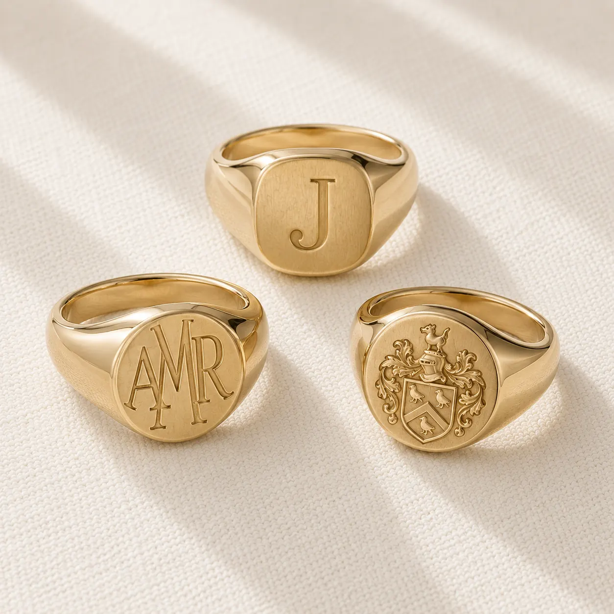 Men's 14K yellow gold signet rings with monogram engraving on slate background at ATL Luxury Jewelers
