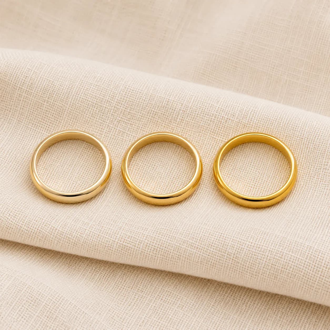 10K, 14K, and 18K yellow gold wedding bands side by side showing the color gradient from palest to richest yellow