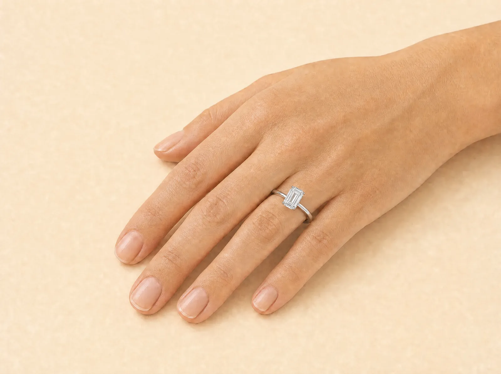 The same hand and platinum band, now holding a rectangular diamond with cropped corners and long parallel facets stepping down to a wide flat top.