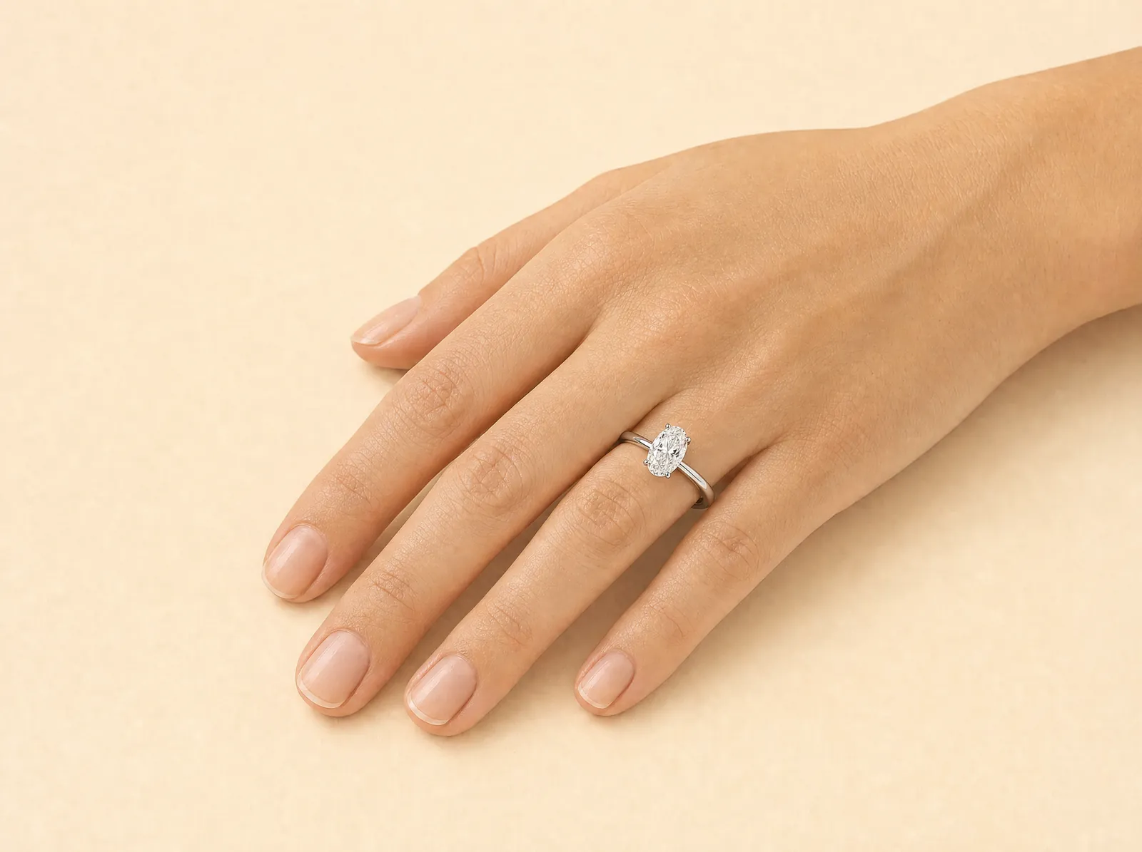 The same hand and platinum band, now holding an elongated rounded diamond that runs the length of the finger.