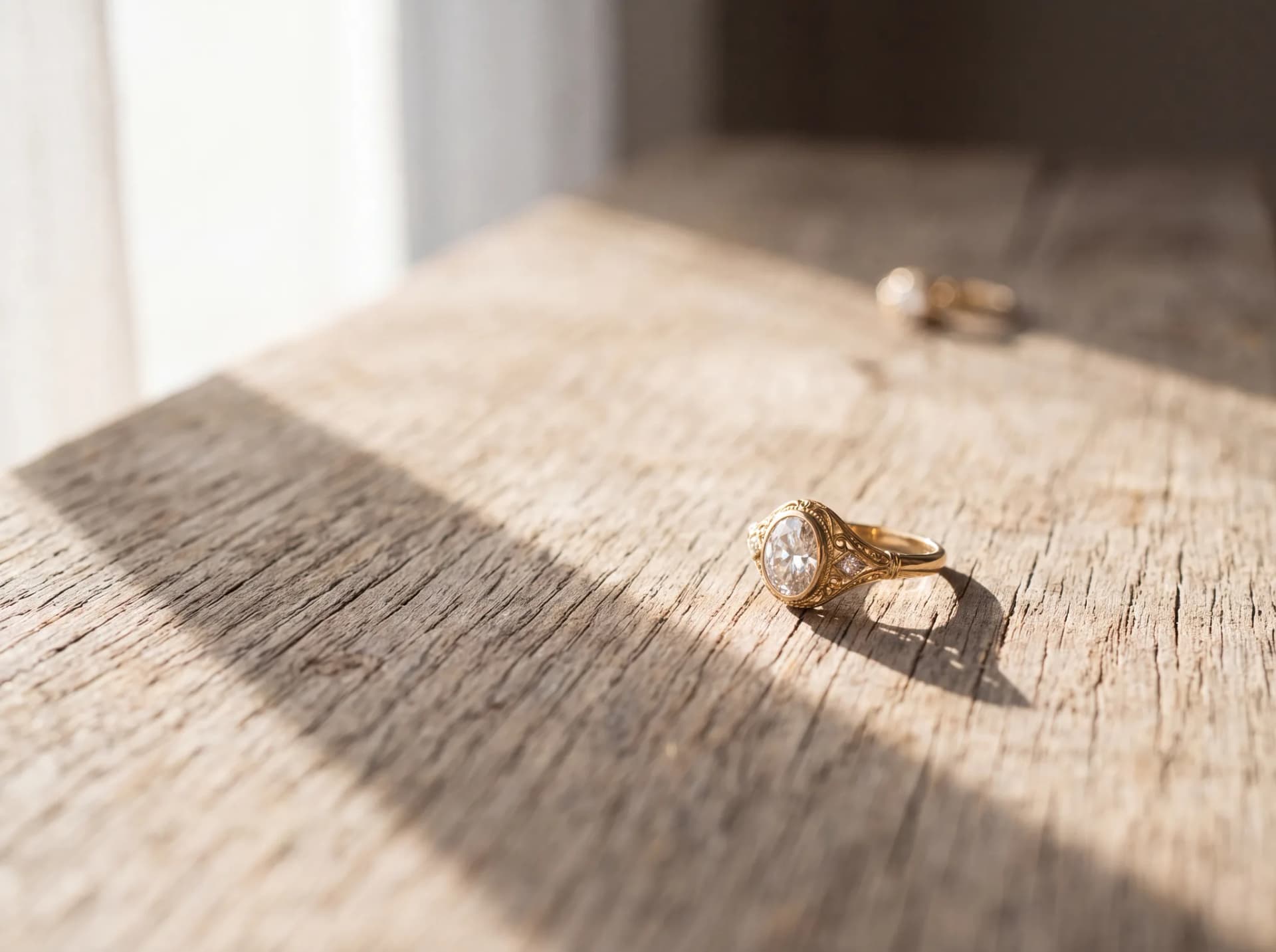 A single gold diamond ring resting alone on a pale wood surface