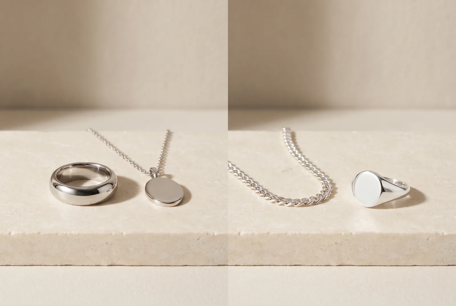 A wide platinum band beside a sterling silver band and a fine silver chain on cream silk over a pale stone slab.