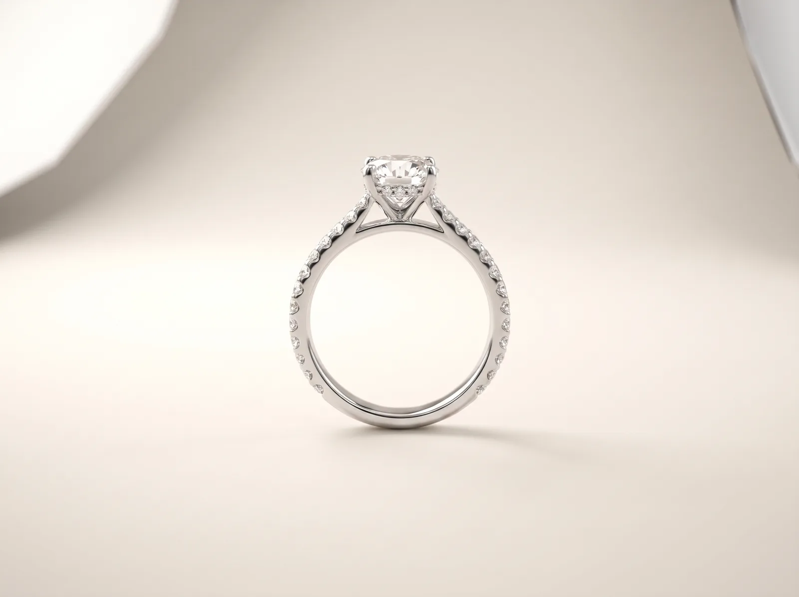A platinum pavé engagement ring standing upright: a round center diamond above a shank lined on both shoulders with small close-set accent diamonds.