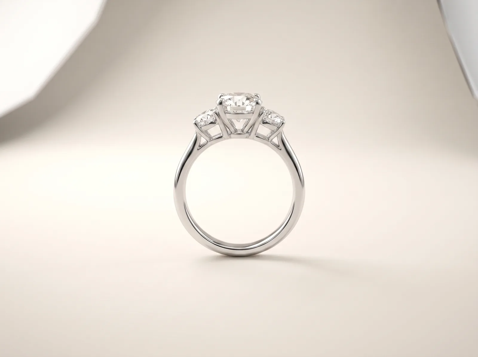A platinum three-stone engagement ring standing upright: a round center diamond with a smaller round diamond set close on either side.