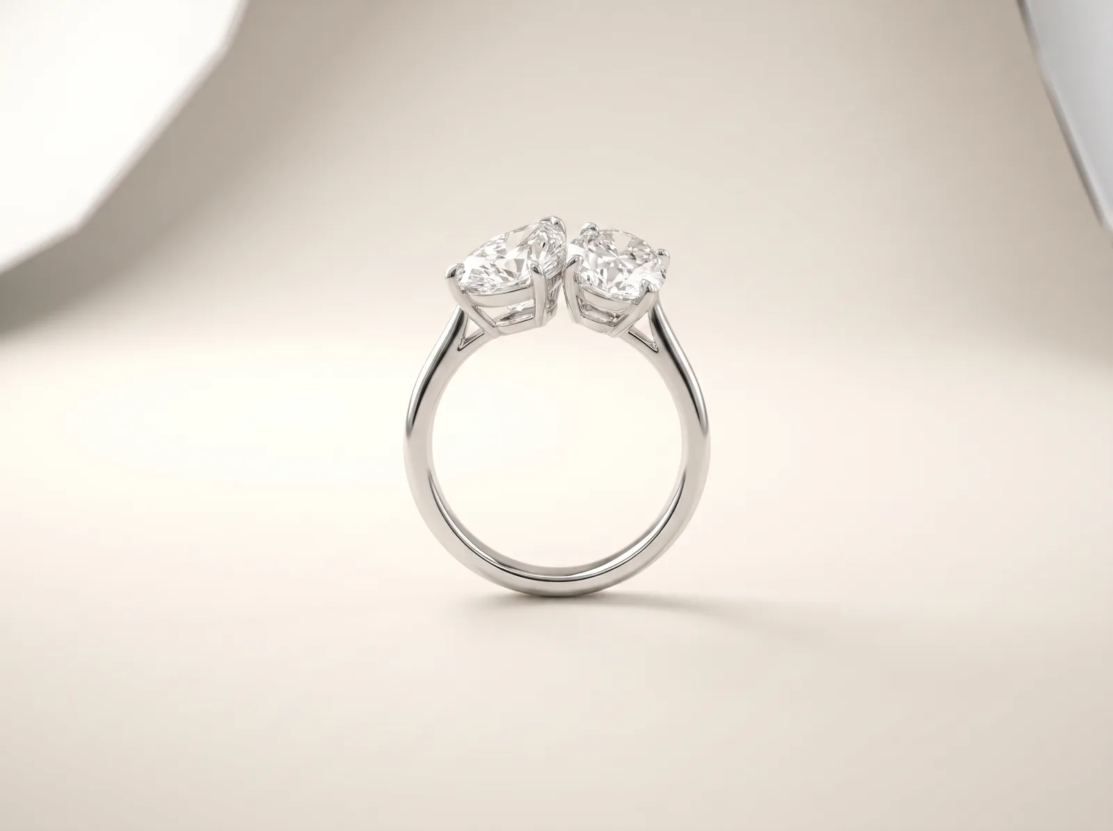 A platinum two-stone engagement ring standing upright: two diamonds of similar size set side by side and angled towards each other, with no single center stone.