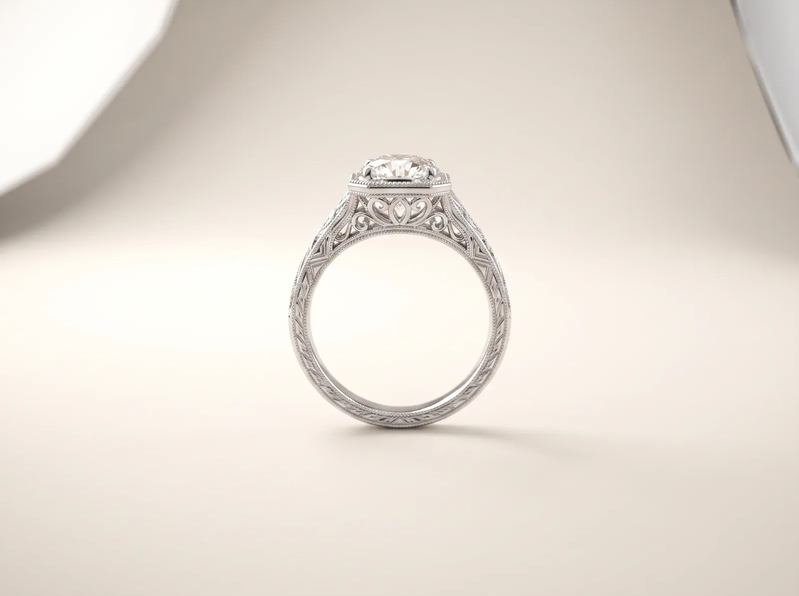 A platinum vintage engagement ring standing upright: a round diamond in a milgrain-edged rim above a pierced, scrolled gallery, with engraving running down the shoulders of the band.