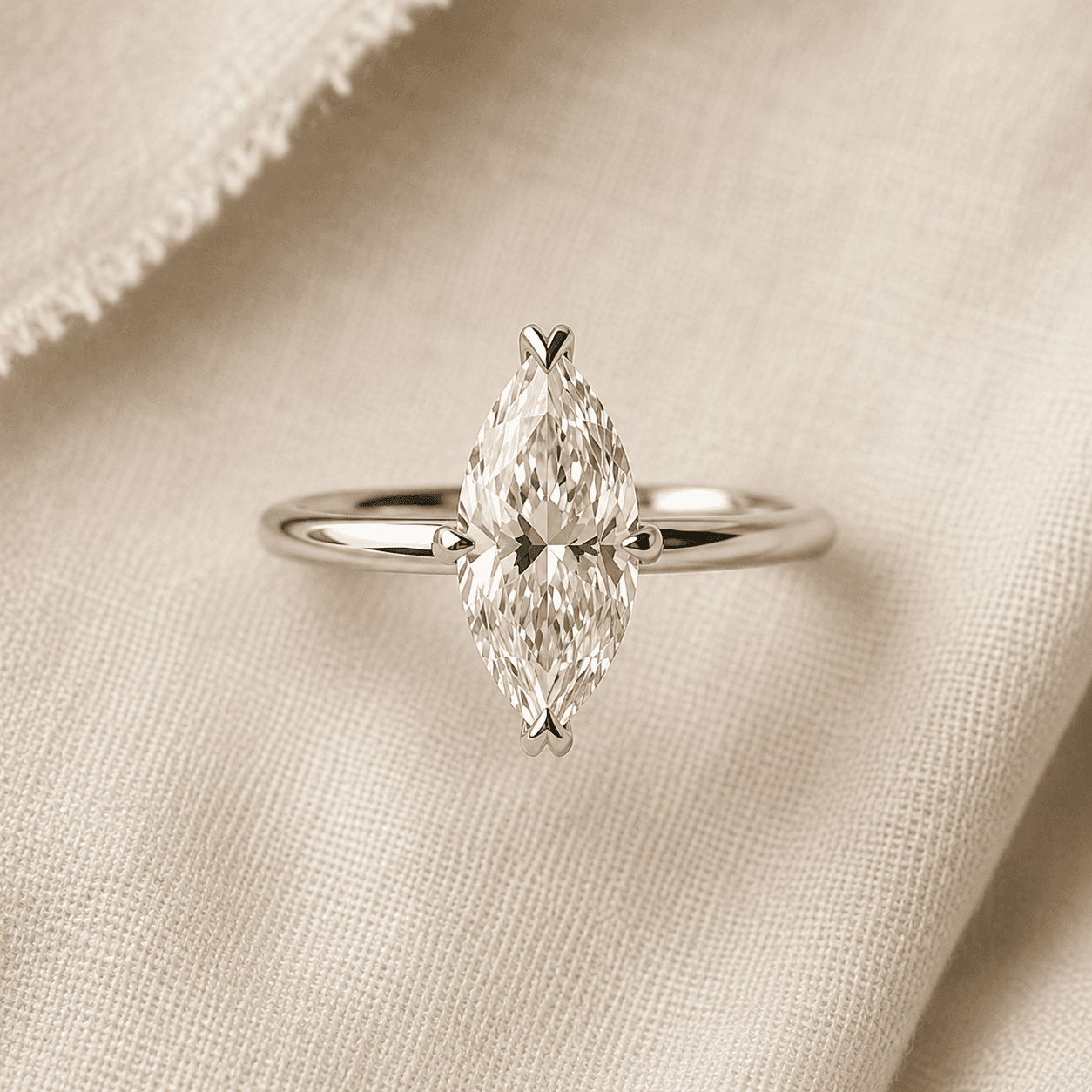 V-prong marquise solitaire engagement ring in white gold on cream linen