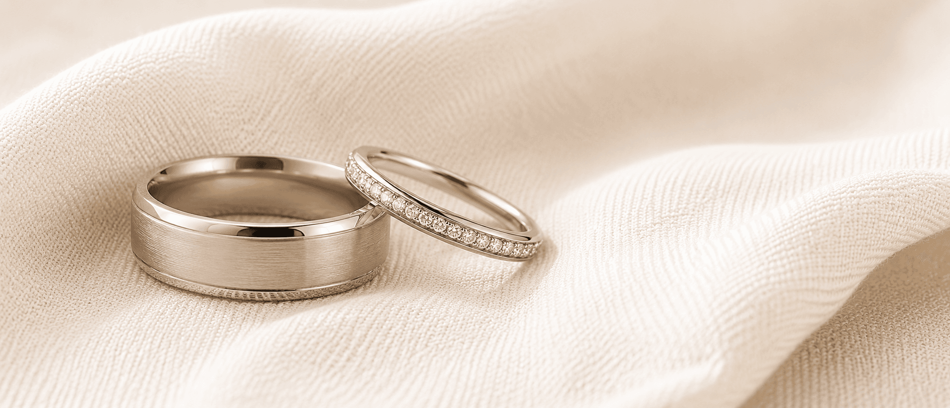 Matching pair of platinum wedding bands resting together on cream linen, handcrafted at ATL Luxury Jewelers in Atlanta