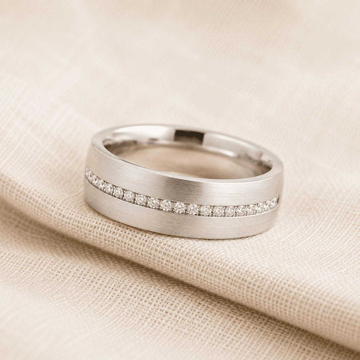Men’sdiamond wedding band in white gold with flush-set row of diamonds on cream linen at ATL Luxury Jewelers Atlanta