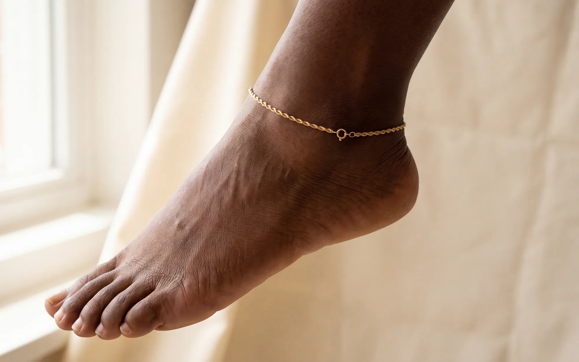 A fine rope-chain anklet on a foot held slightly pointed
