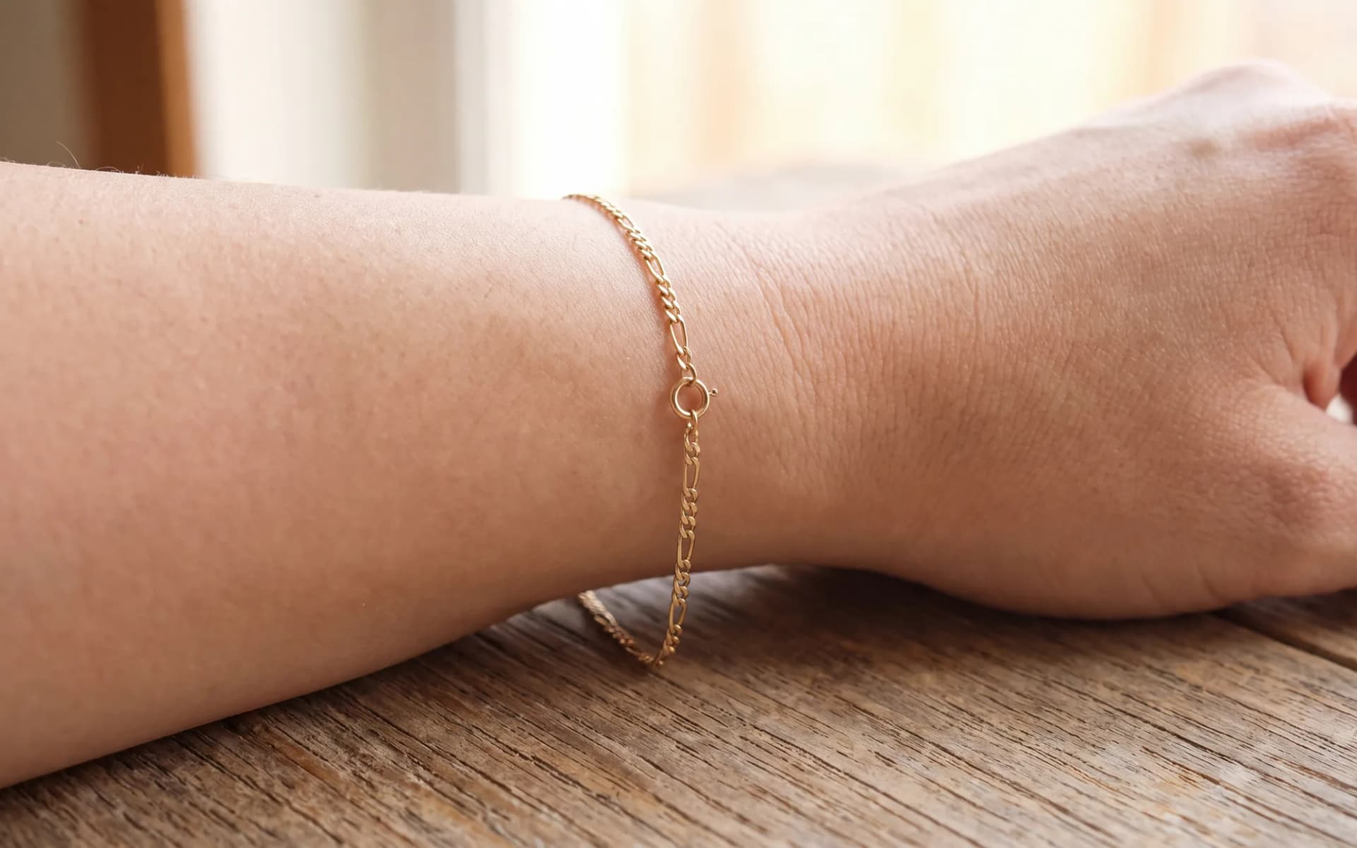 A fine figaro chain bracelet on a wrist, seen from the side