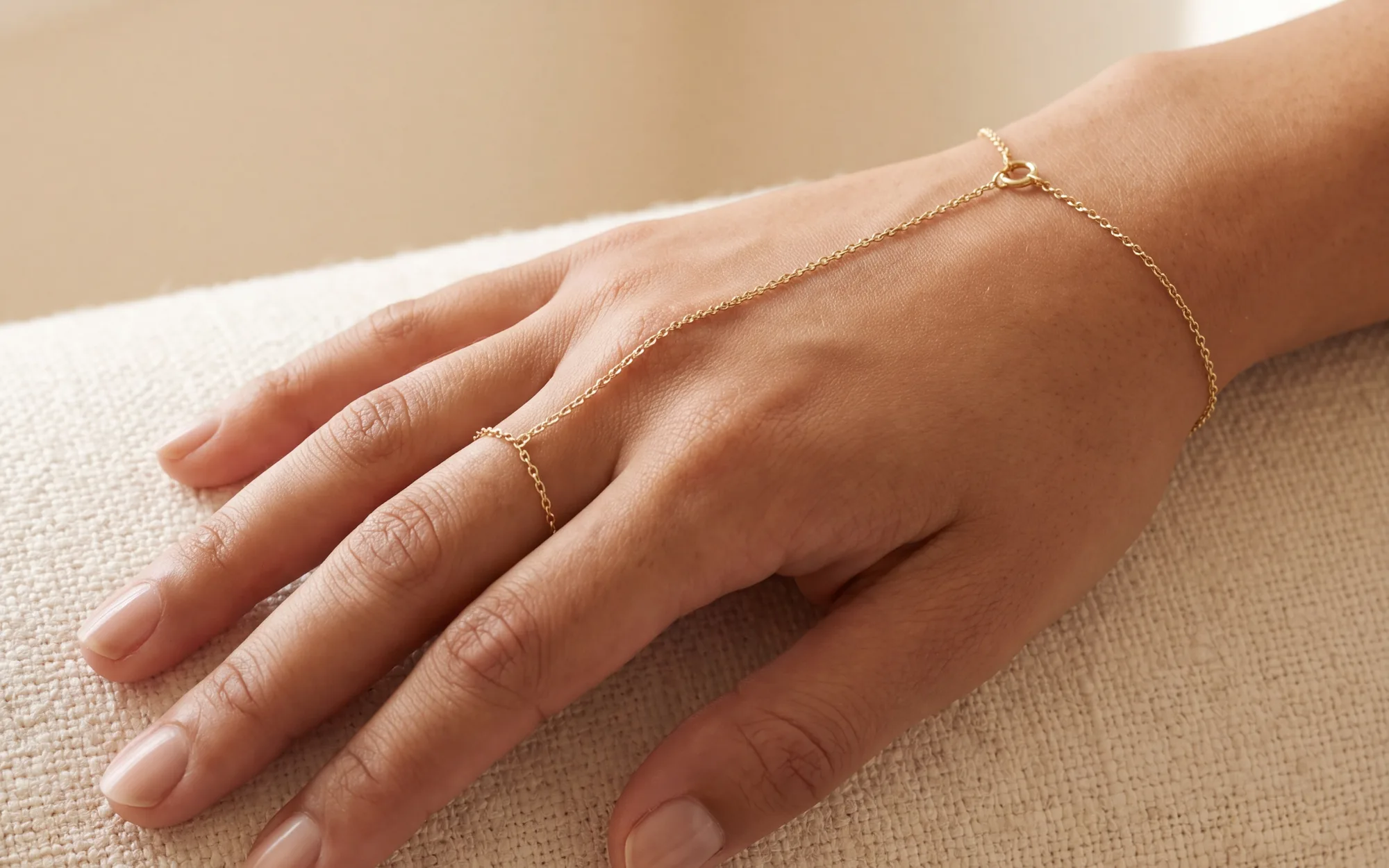 A fine hand chain running from a finger ring to a wrist bracelet across the back of a hand