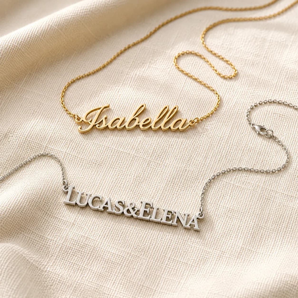 Two-name gold nameplate necklaces in script and block letters on cream linen at ATL Luxury Jewelry Atlanta
