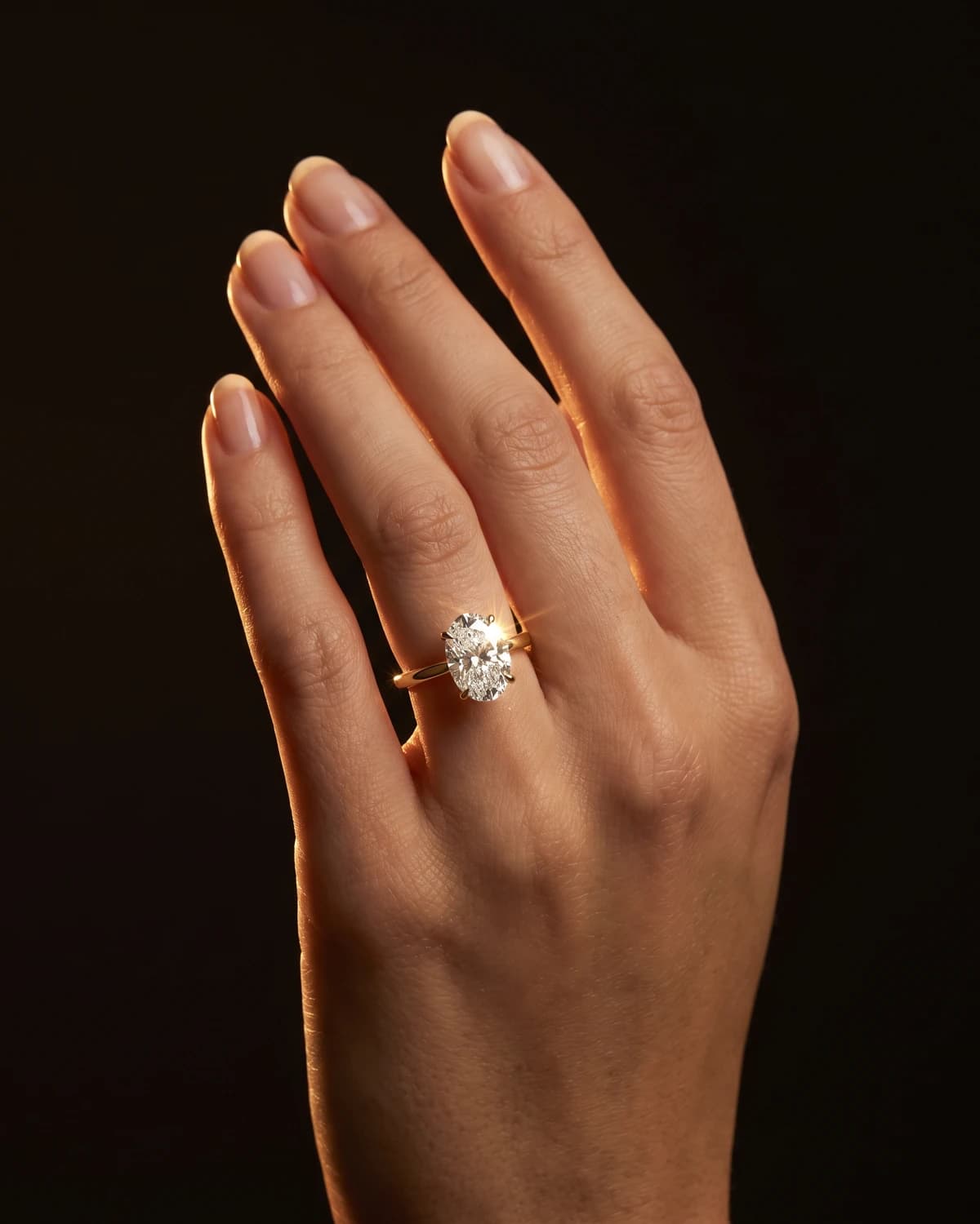 Design prototype — a rendering of an oval diamond solitaire ring in a plain yellow gold band, worn on the ring finger, a piece ATL Luxury Jewelry can make for you.