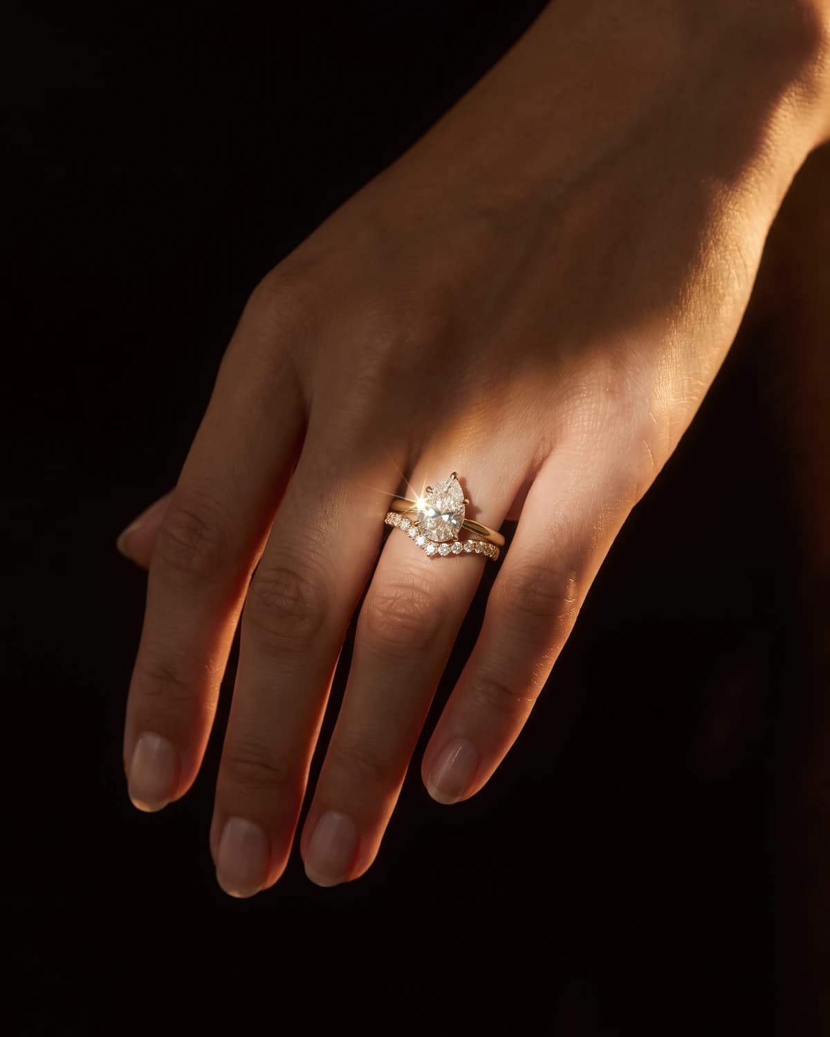 Design prototype — a rendering of a pear-shaped diamond ring stacked with a curved pavé diamond wedding band, worn on the ring finger, a piece ATL Luxury Jewelry can make for you.