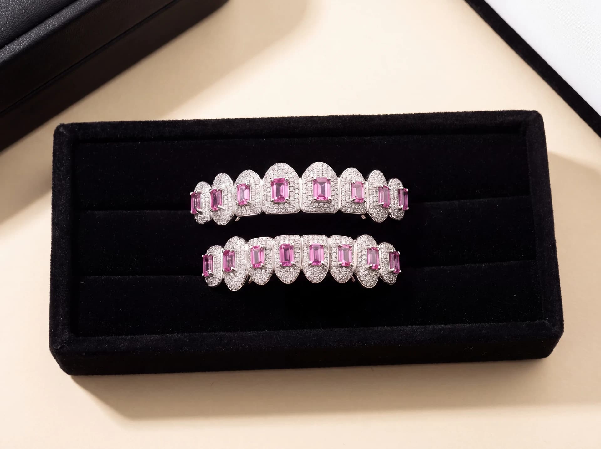 A top-and-bottom fully iced white gold custom grillz set with pink emerald-cut stones, in a display box.