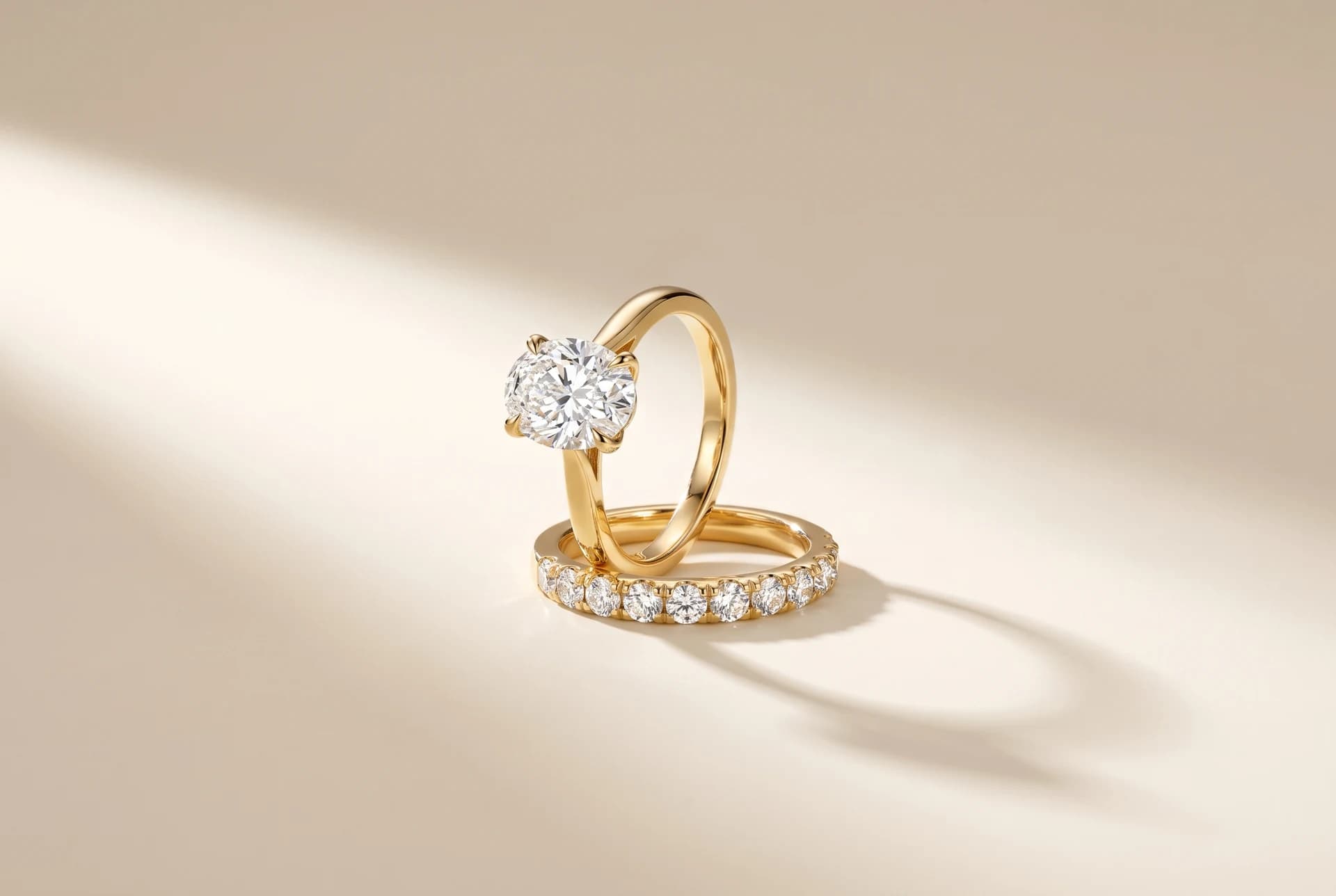 A yellow gold oval solitaire engagement ring standing behind its matching diamond wedding band, a design prototype by ATL Luxury Jewelry