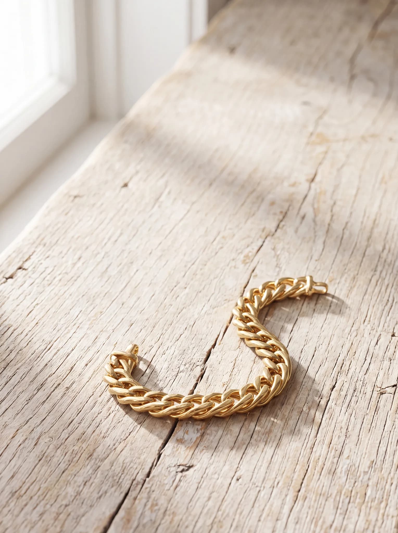 A yellow gold link bracelet resting on a pale wood surface at ATL Luxury Jewelry, Snellville GA