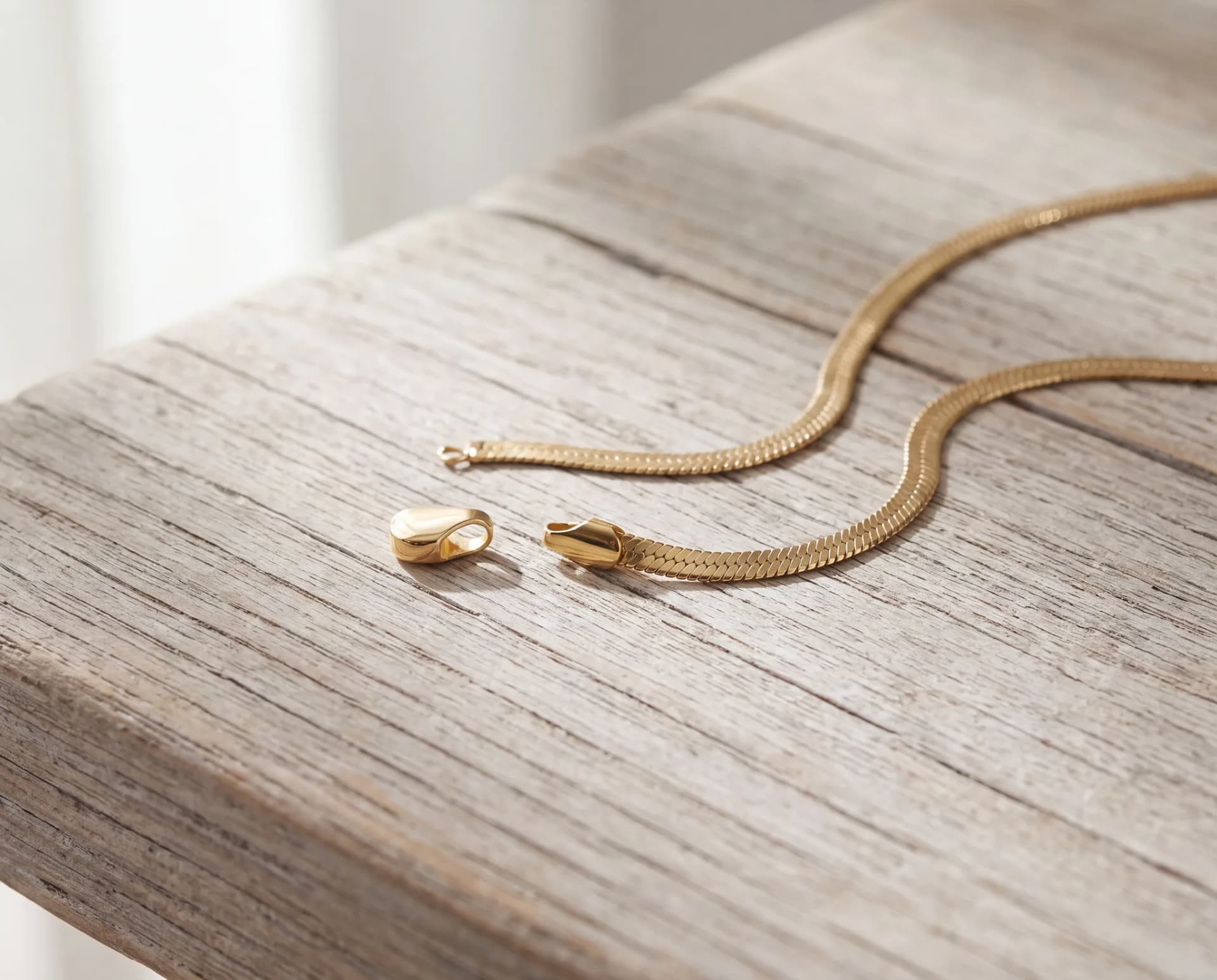 A chain end cap pulled loose from its links, resting on a pale wood surface