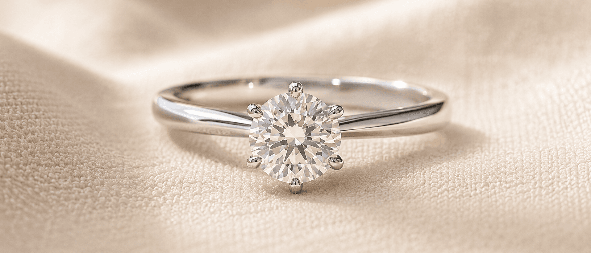 Solitaire diamond engagement ring on a cream linen surface, handcrafted at ATL Luxury Jewelers in Atlanta