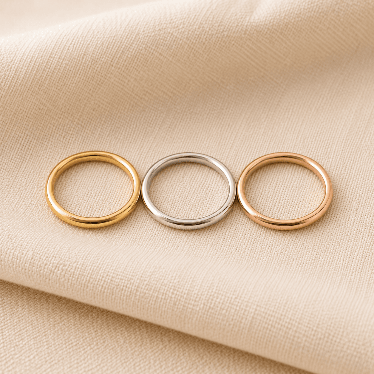 Gold stackable rings in yellow, white, and rose gold layered on cream linen at ATL Luxury Jewelers Atlanta