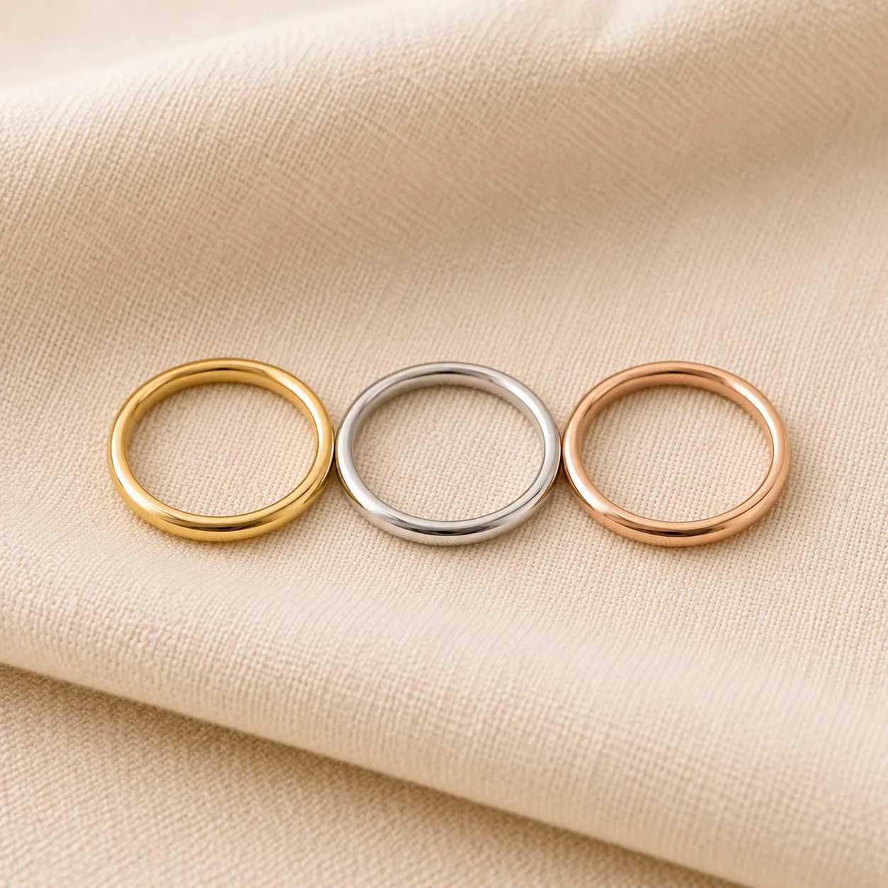 Gold stackable rings in yellow, white, and rose gold layered on cream linen at ATL Luxury Jewelry Atlanta