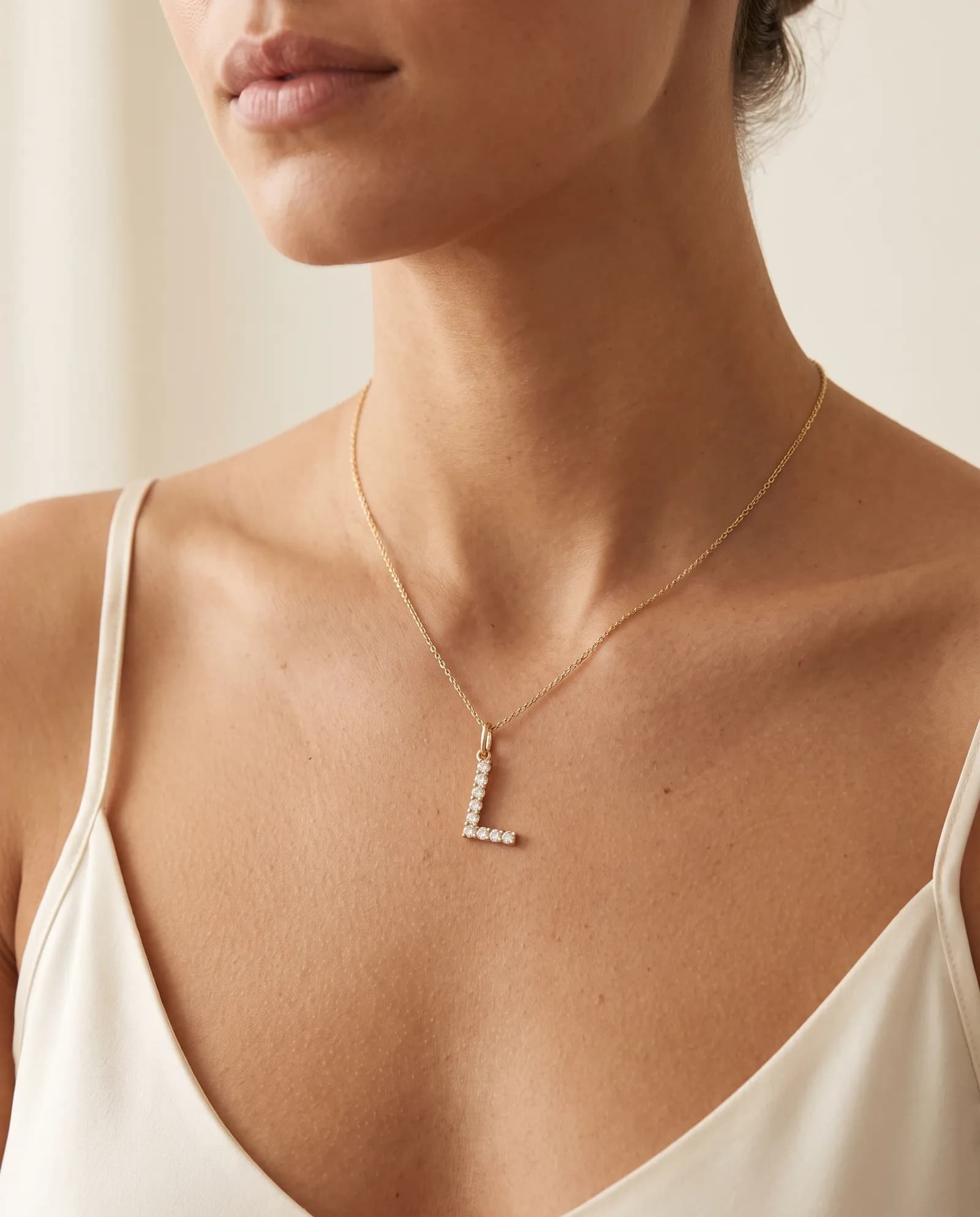 Diamond-accented gold initial necklace worn at the collarbone