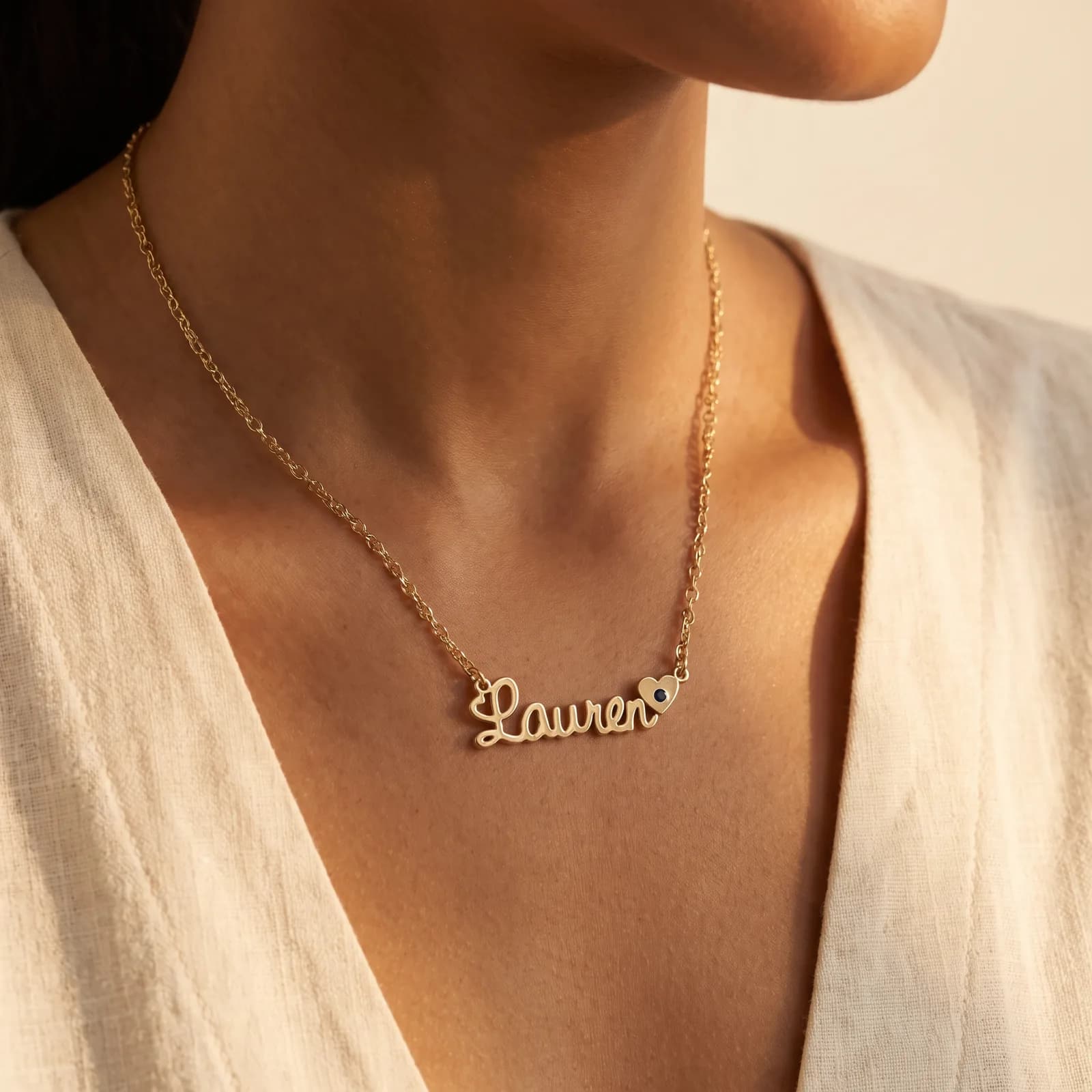 Gold script nameplate necklace with accent stone worn