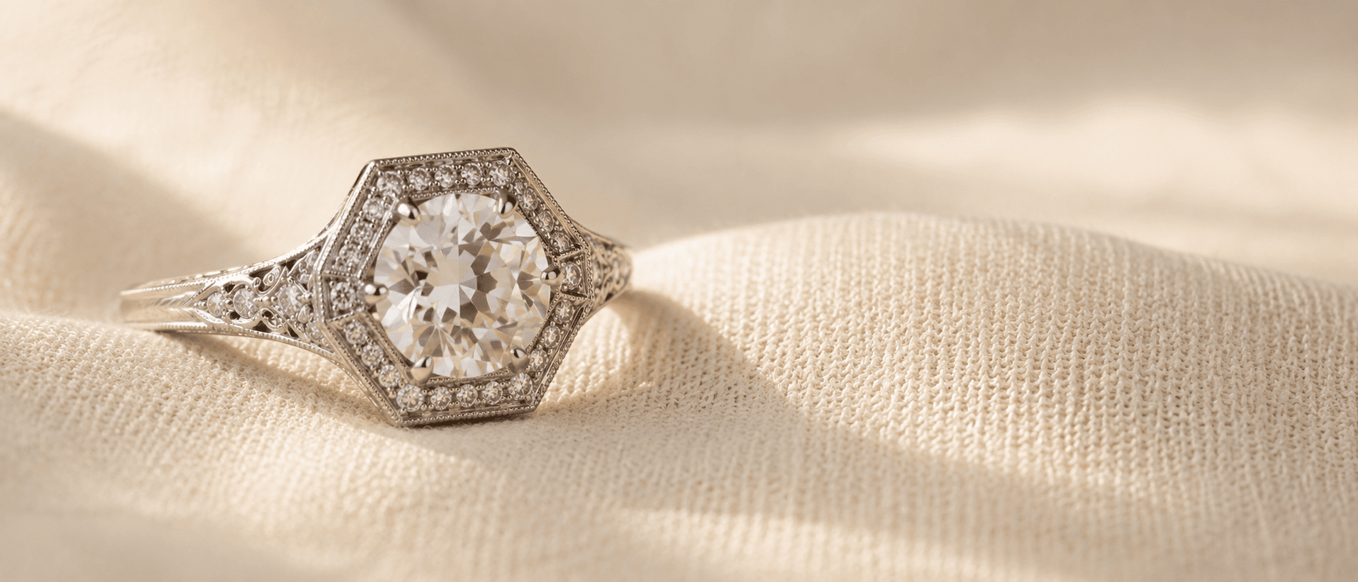 Art Deco engagement ring with hexagonal halo and milgrain on cream linen at ATL Luxury Jewelers Atlanta