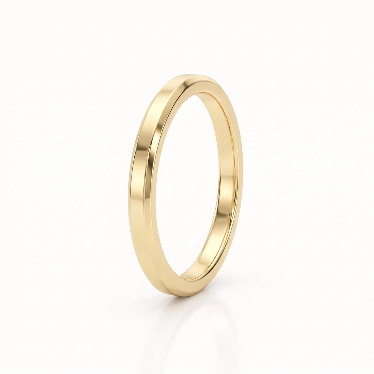 A slim yellow gold wedding band with bevelled edges, seen at a slight angle on a pale background