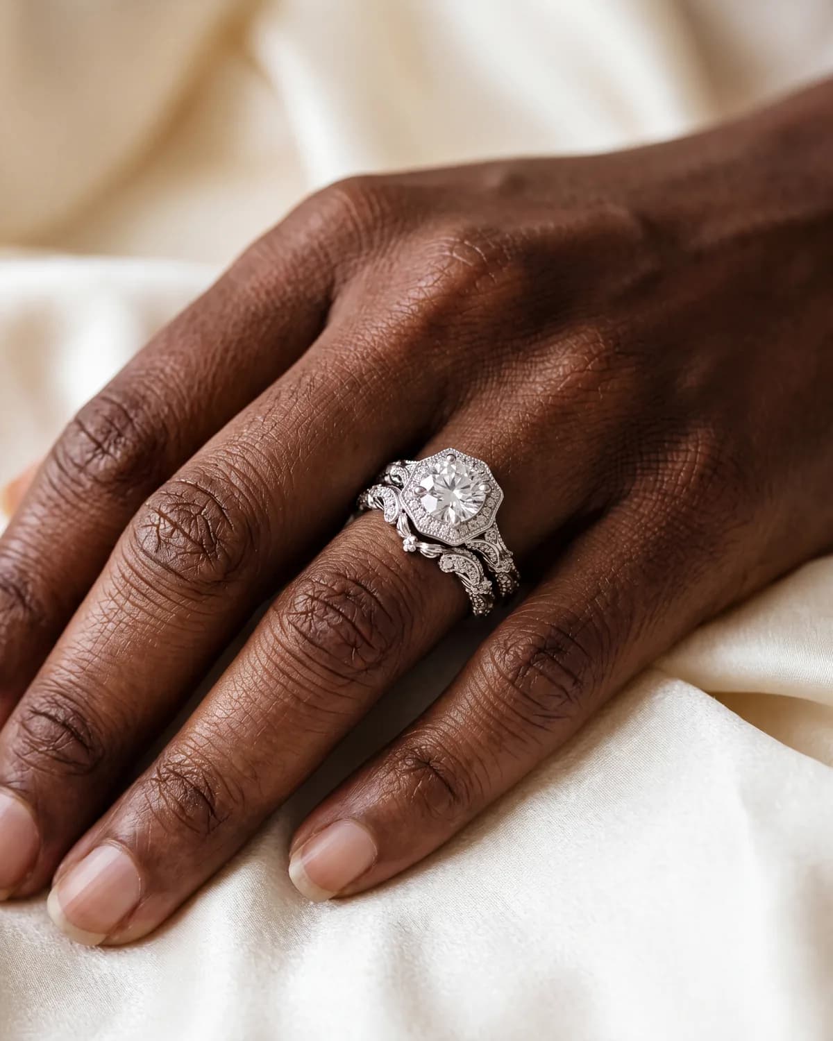 A hand wearing a halo engagement ring with a curved wedding band following the line of the halo