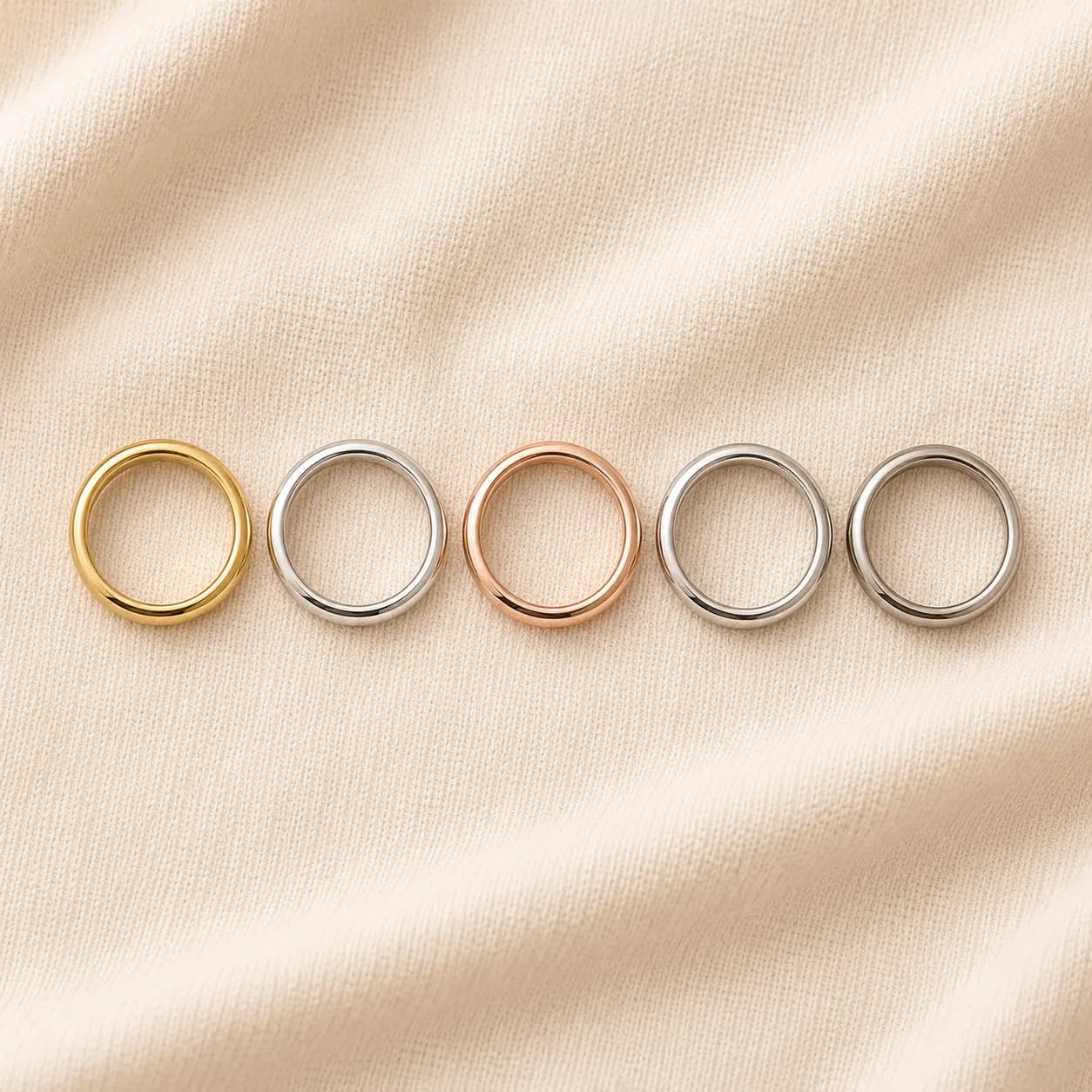 Five wedding bands showing the spectrum of metals — yellow gold, white gold, rose gold, platinum, and palladium — on cream linen at ATL Luxury Jewelry Atlanta